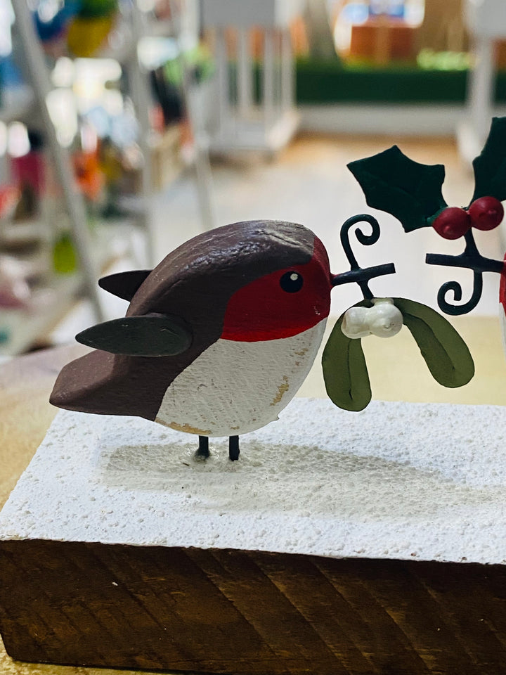 Wooden robin decoration with mistletoe on a white surface