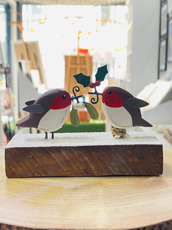 Decorative wooden birds with mistletoe on a wooden base in a store setting