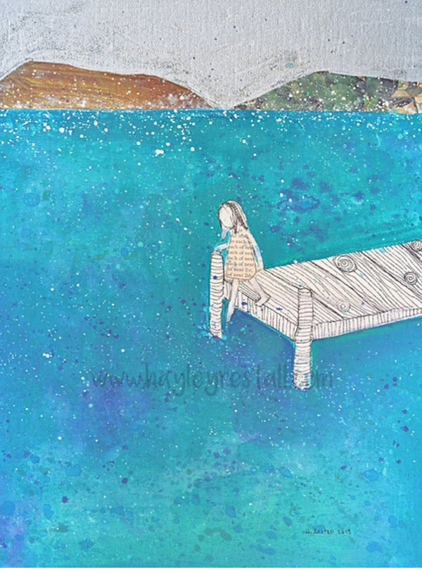 Person sitting on a dock over a blue water body with a mountainous background