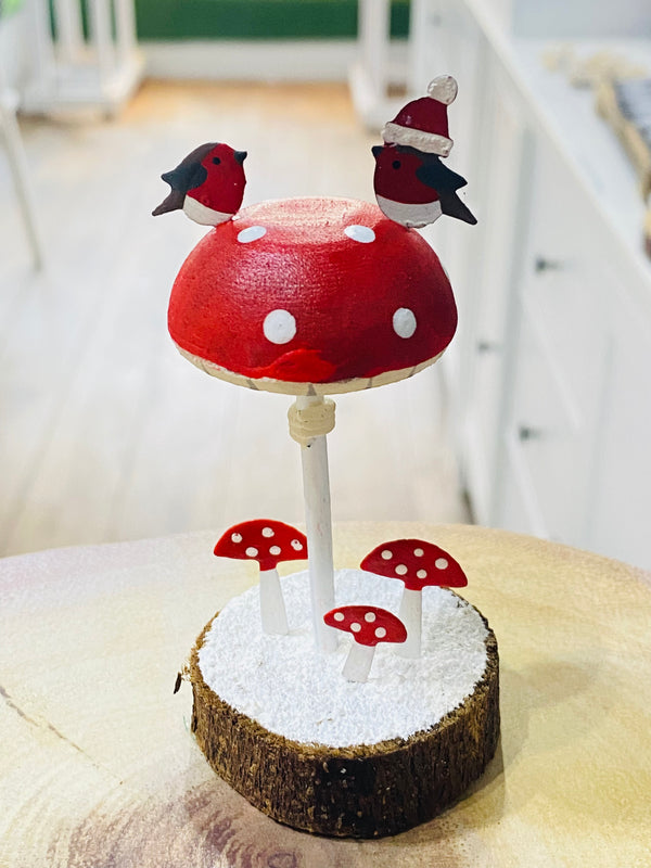 Decorative mushroom with birds on top, resembling a toadstool, on a white surface.