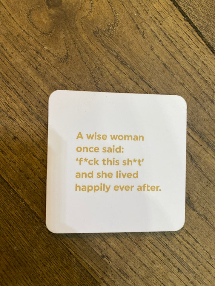 A white coaster with gold writing saying a wise woman nce said f this shit and she lived happily ever after